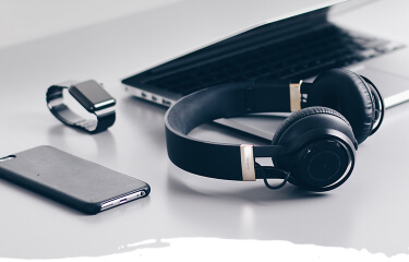 Table with smartphone, laptop, headphones and smartwatch on top
